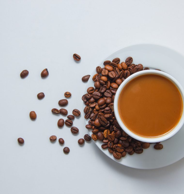 Top view a cup of coffee with coffee beans on saucer on white background